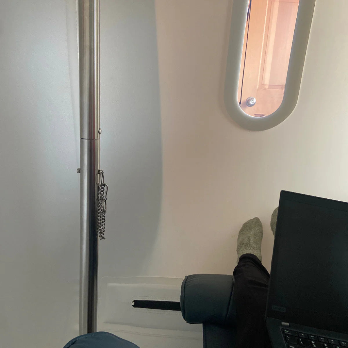 Sitting hyperbaric chamber with person sitting inside on their laptop
