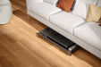Folded treadmill stored under a couch in a modern home