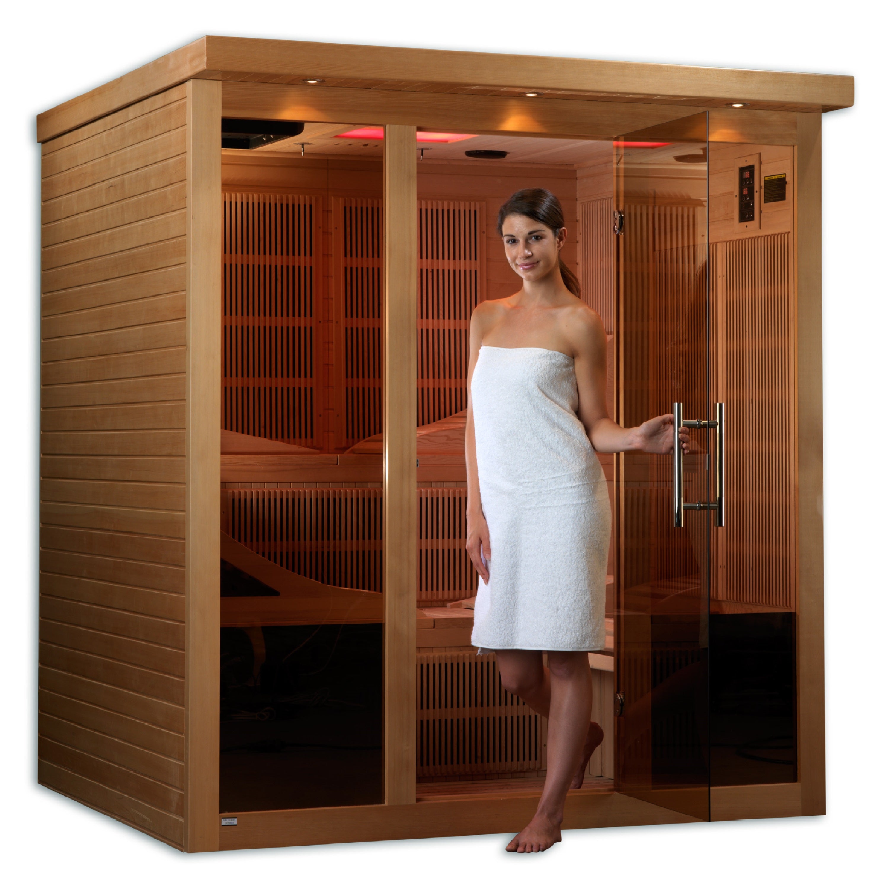 Woman standing in a wooden infrared sauna with a white towel wrapped around her.