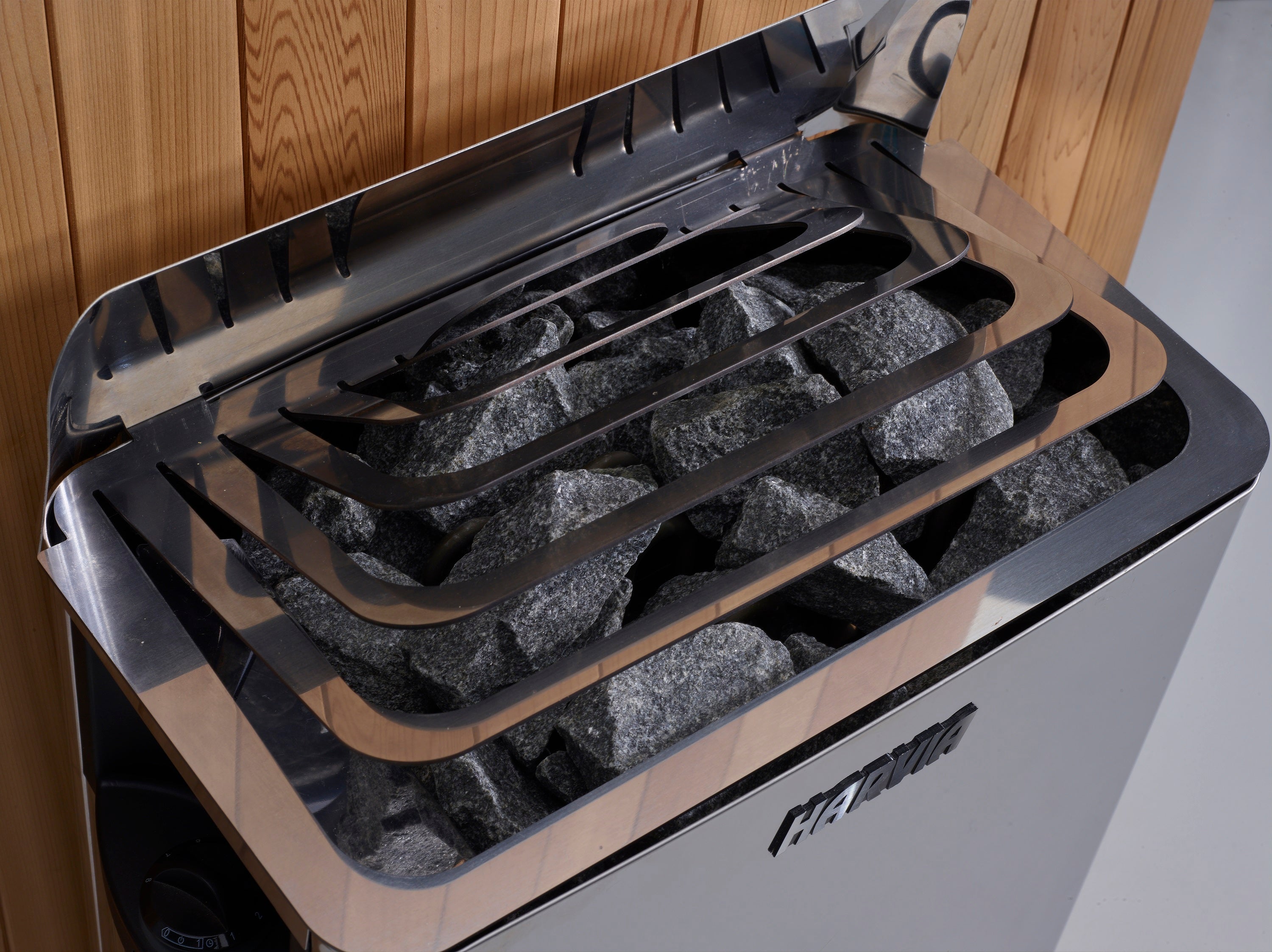 Portable stove with rocks inside, against a wooden wall.