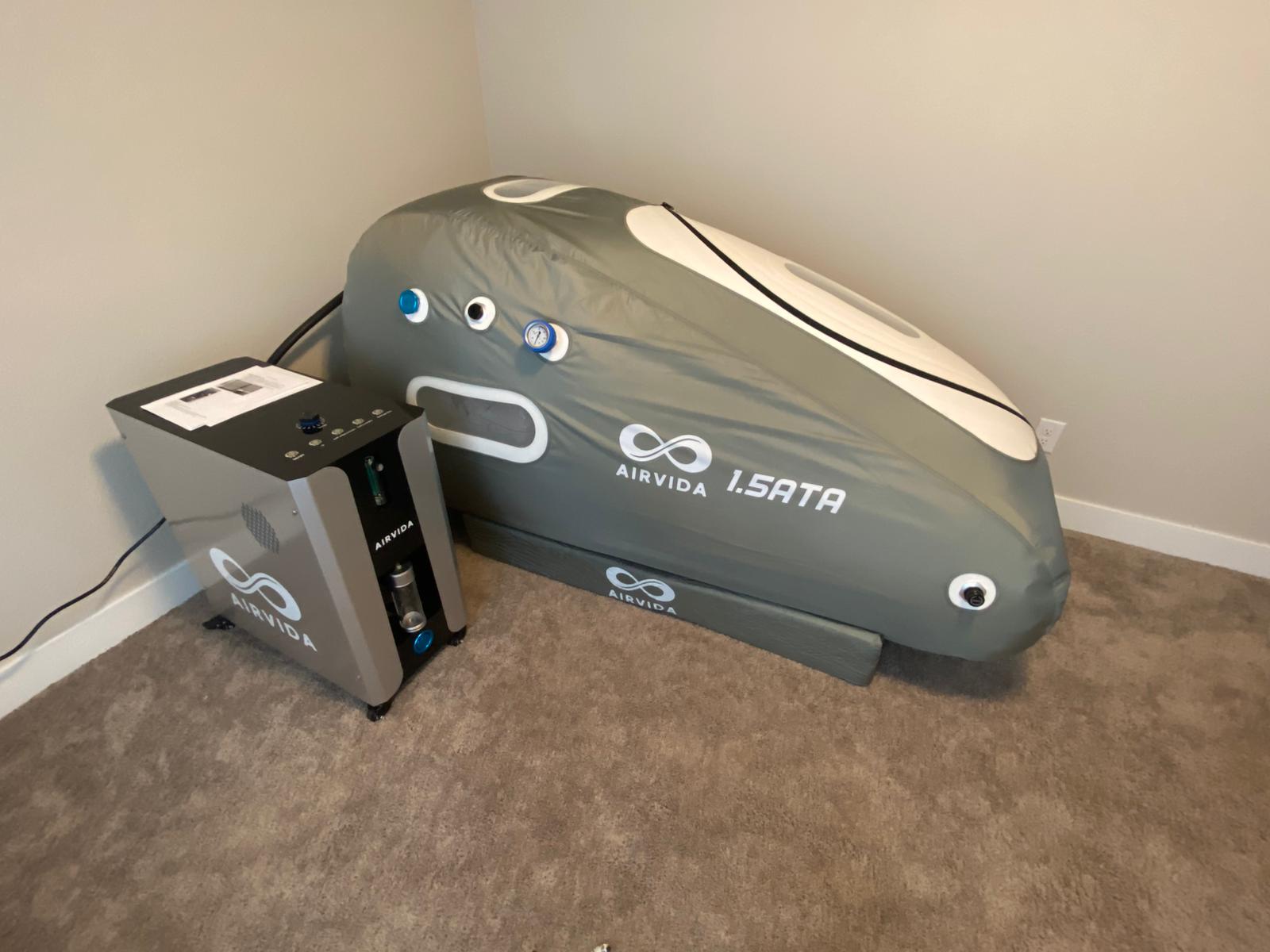 Gray hyperbaric chamber with 'AIRVIDA' branding on a carpeted floor.