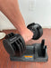 Person using a pair of adjustable dumbbells on a wooden floor.