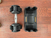Black adjustable dumbbell and its packaging on a wooden surface
