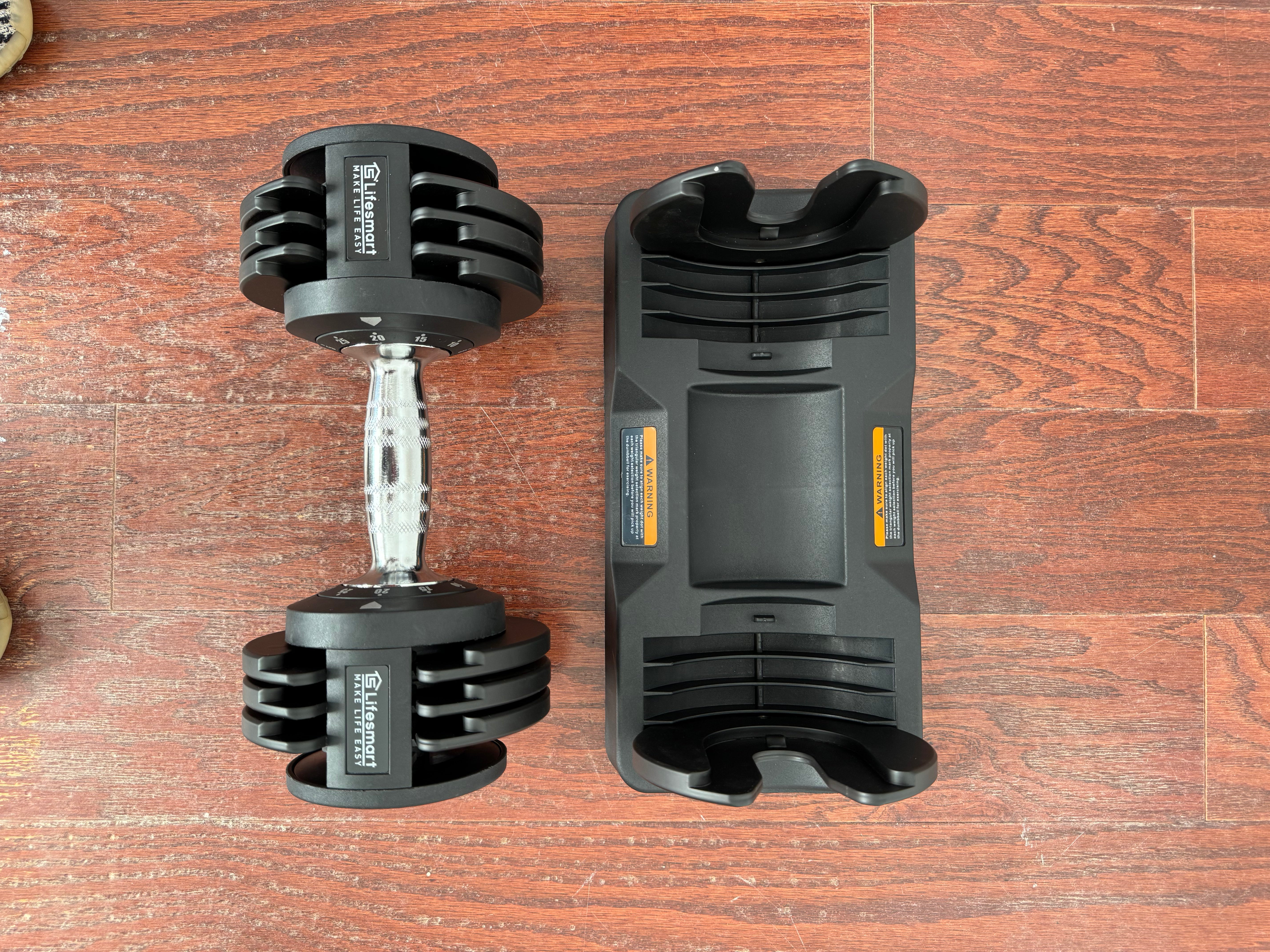 Black adjustable dumbbell and its packaging on a wooden surface