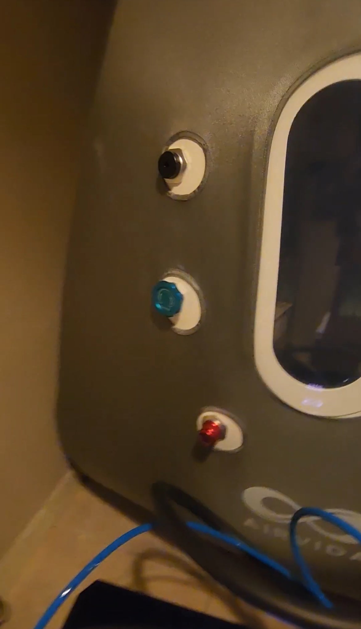 Sitting hyperbaric chamber with gauges in a tan room on a tile floor
