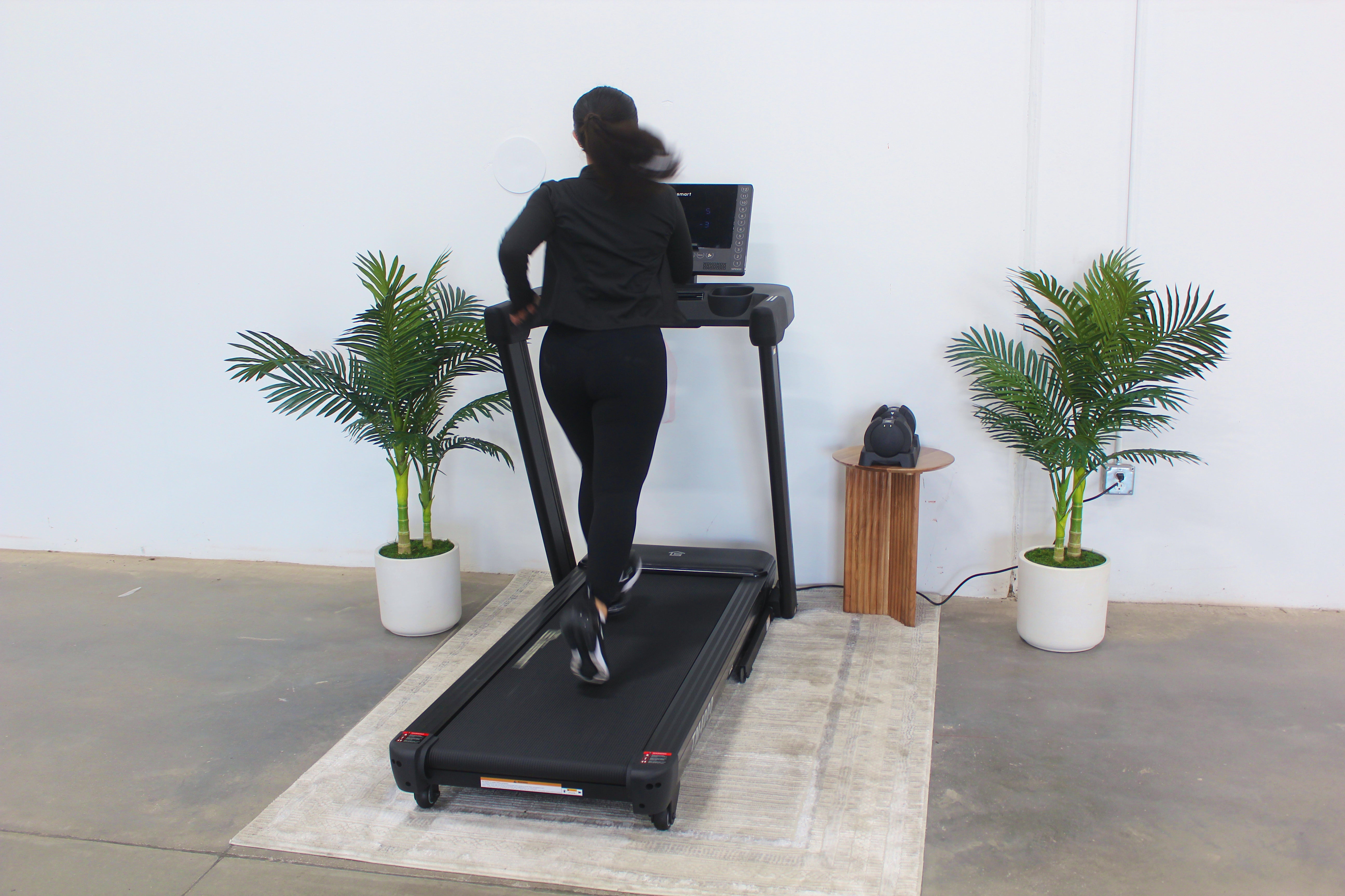 Person using a treadmill in a room with plants and minimal decor