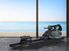 Rowing machine on a marble floor with a large window view of the ocean.