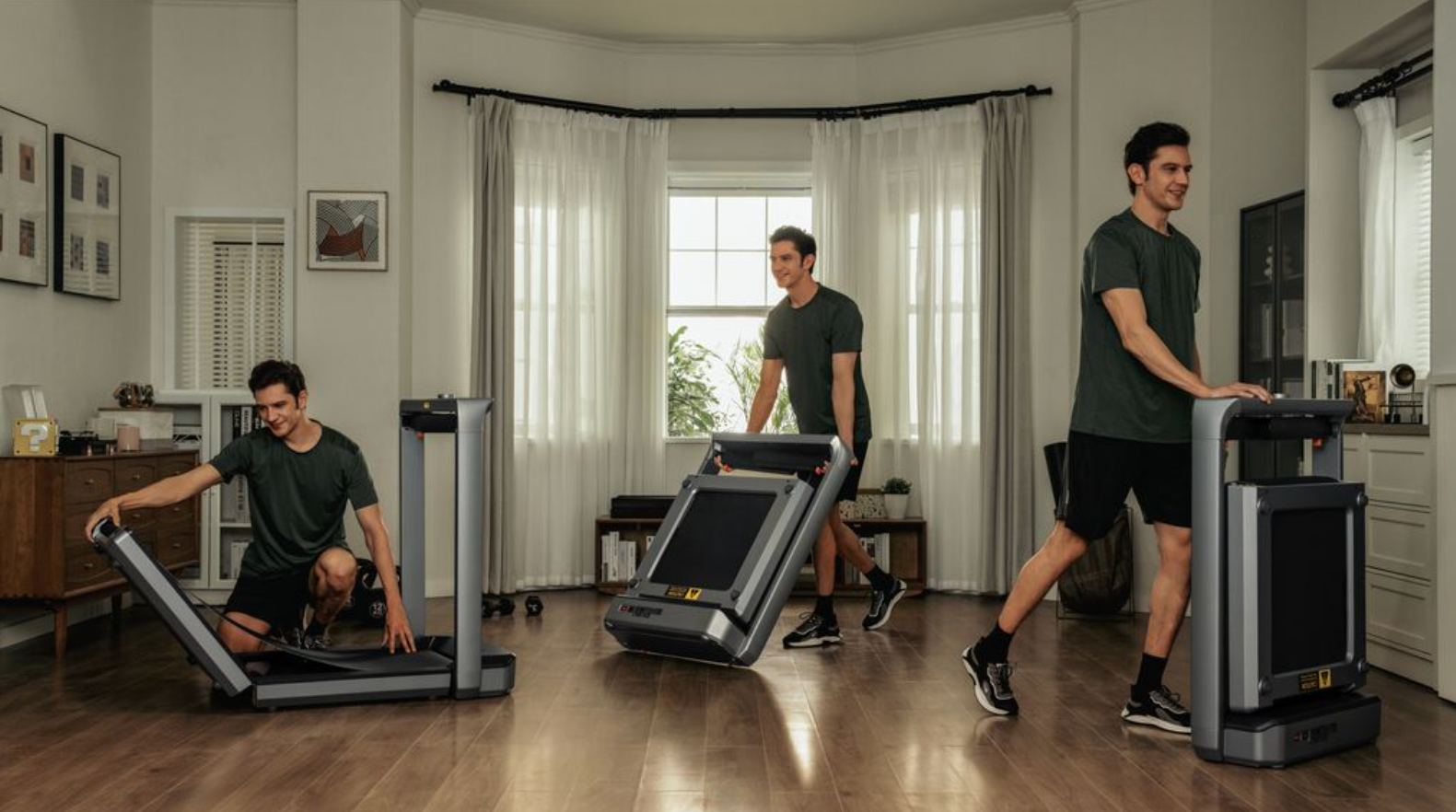 Three men using treadmills in a home setting with large windows and curtains.