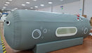 Gray and white hyperbaric chamber in a white room on a wooden floor