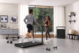 Two people exercising in a modern home gym with a treadmill and dumbbells.