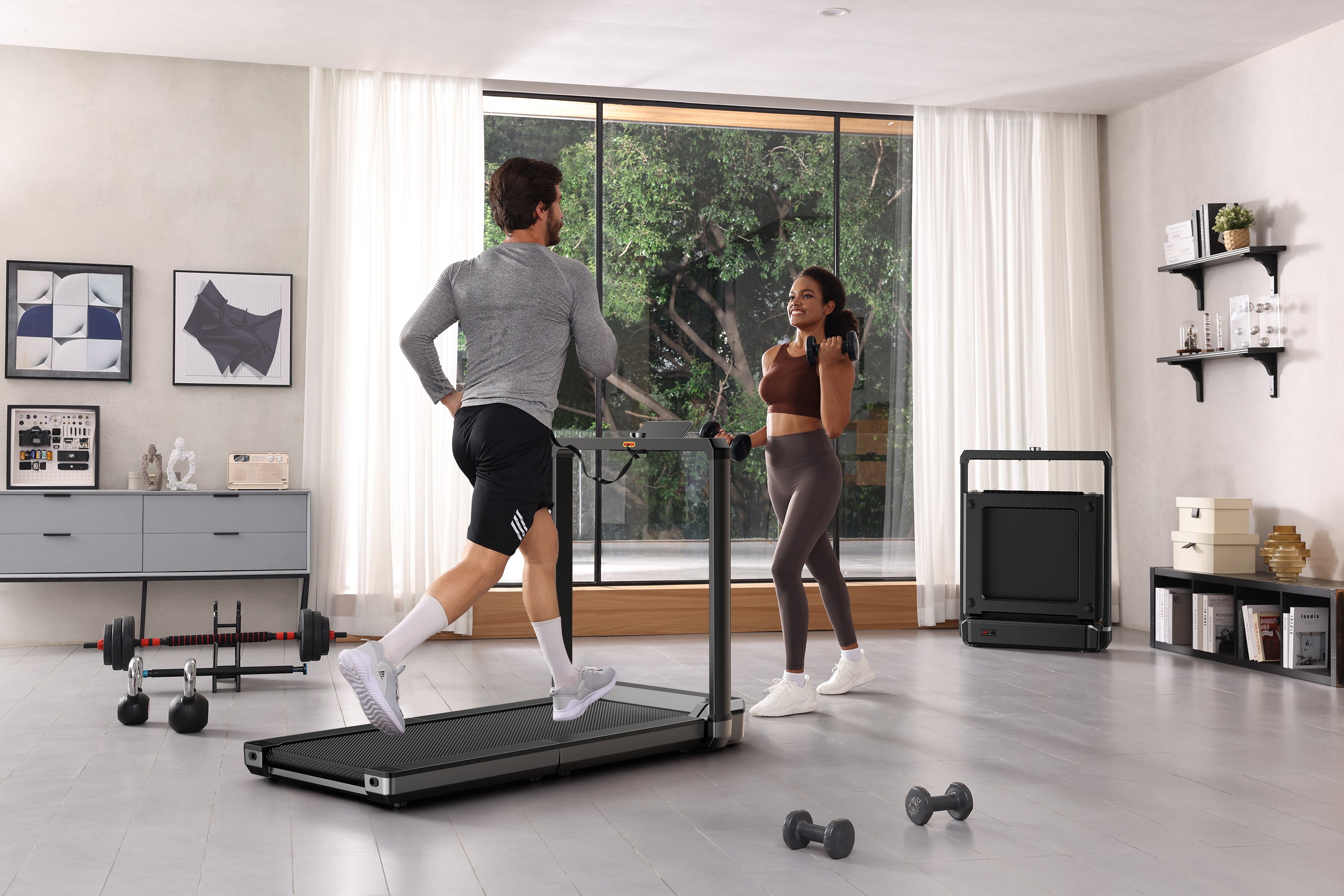 Two people exercising in a modern home gym with a treadmill and dumbbells.