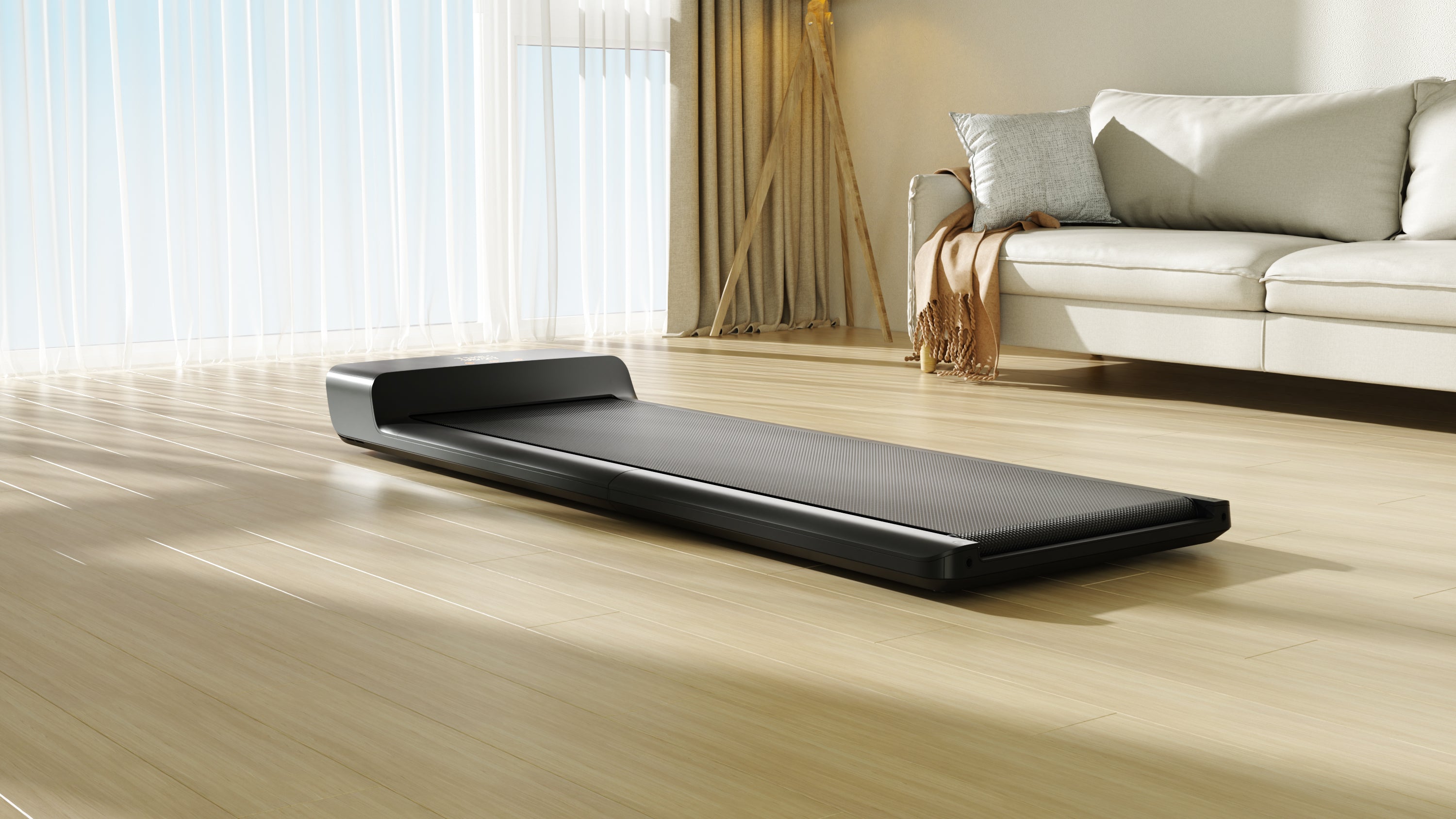 Black electronic walking pad on a wooden floor with a modern living room in the background